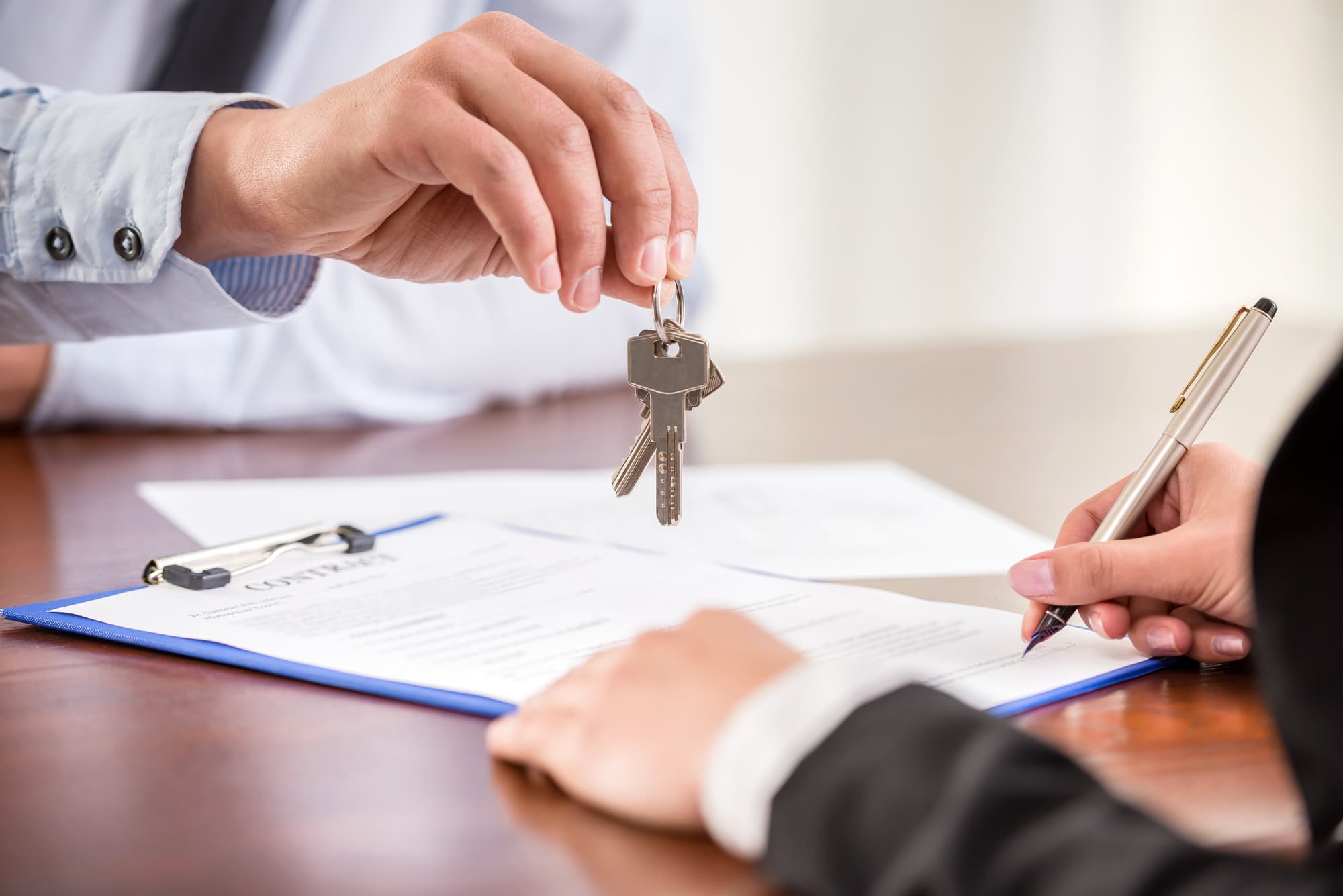 Man handing over the keys to a house after client signs documents