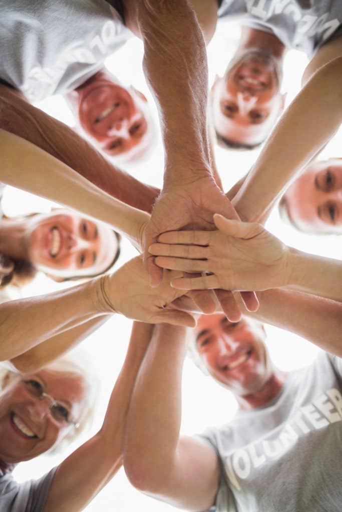 Group of people looking down at the camera with their hands intertwined
