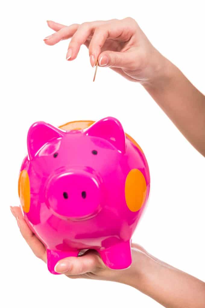 A hot pink piggy bank with a woman's hand inserting a coin