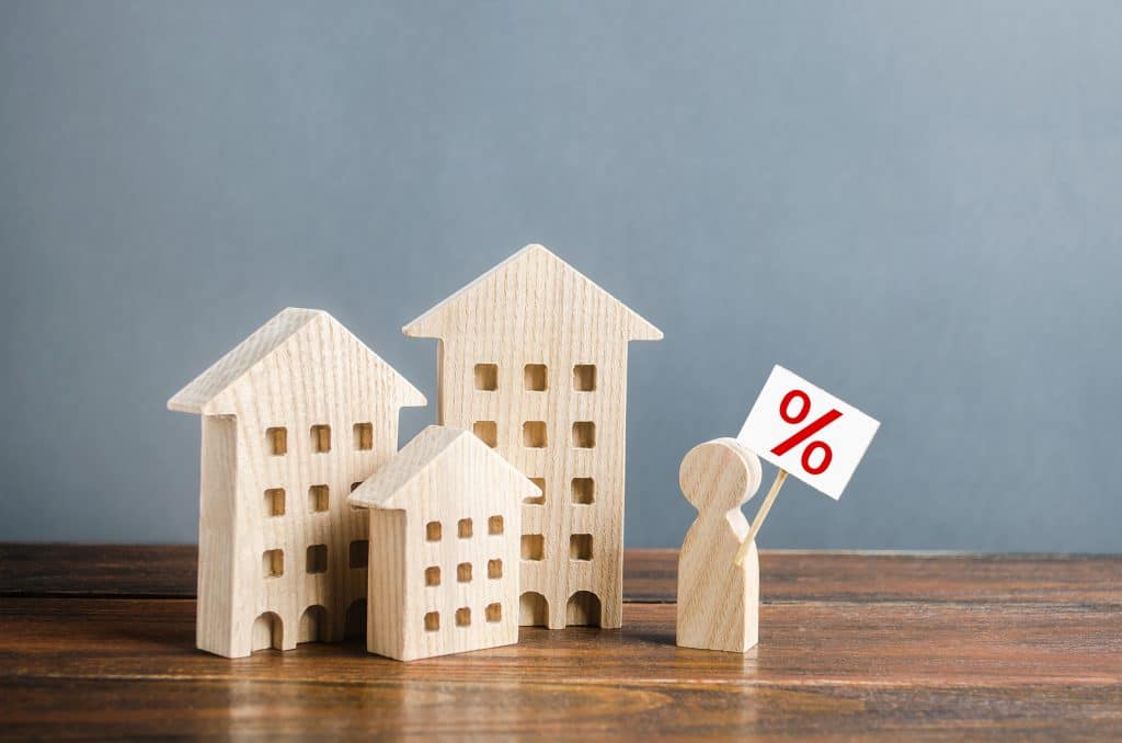 wooden toy houses with wooden figure holding percent sign