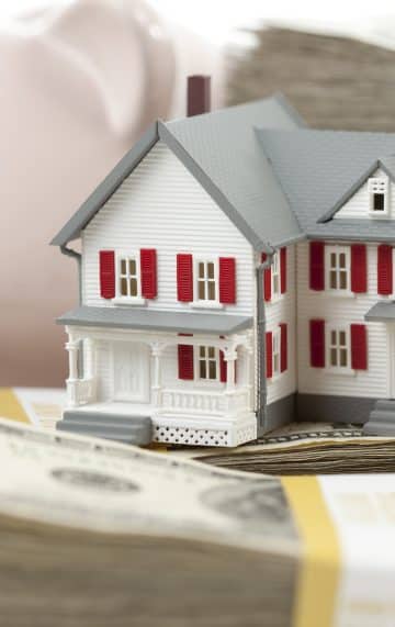 What is Escrow? - small model of house next to piggy bank and stacks of cash