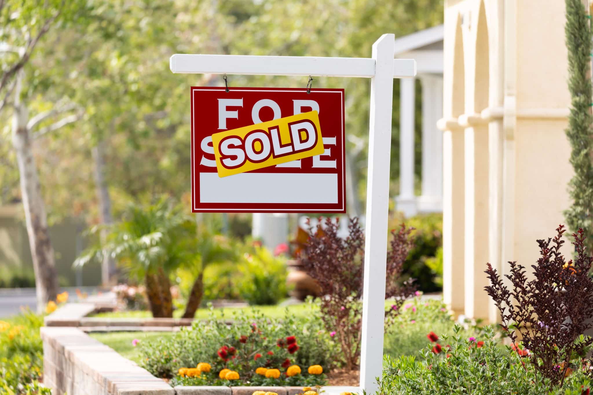A For Sale sign with a Sold sticker on it out in front of a recently sold home.